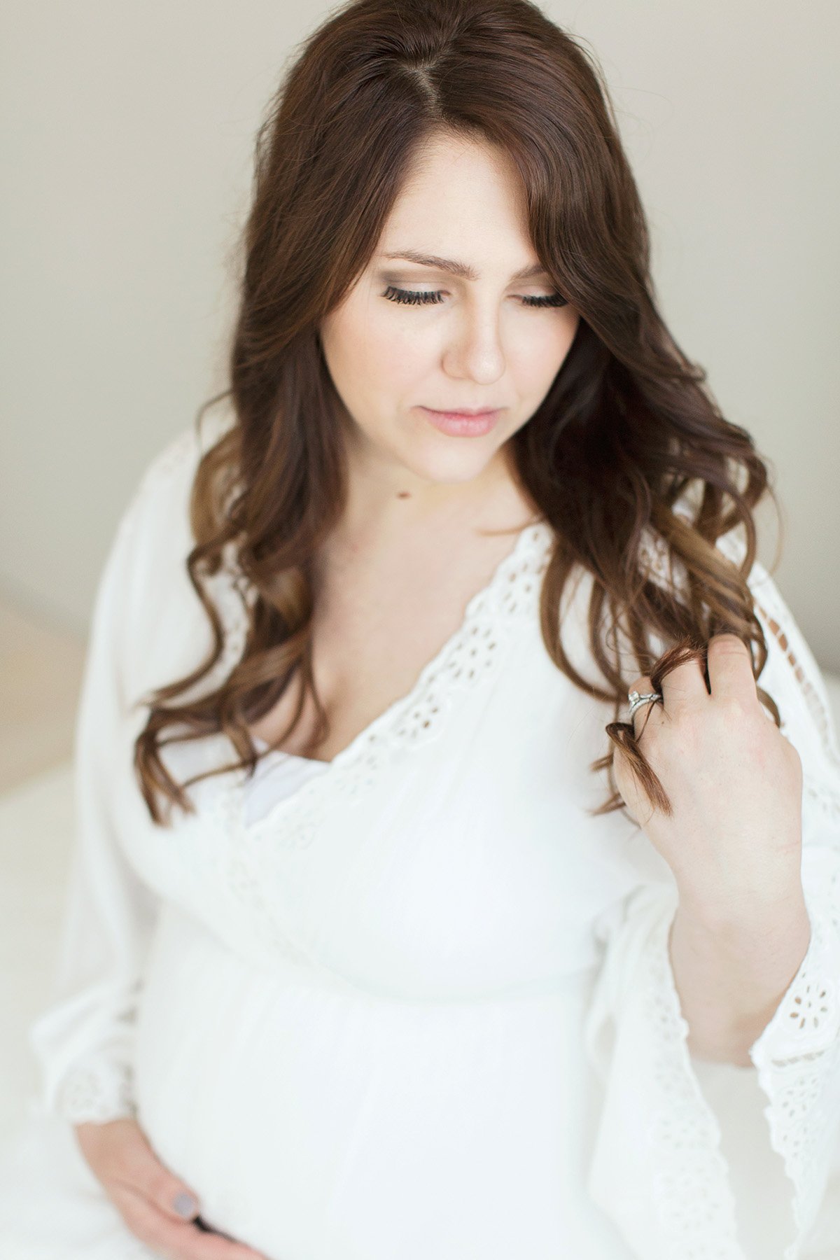 Pregnant mother poses wearing white dress borrowed from Julie Brock Photography Studio in Louisville KY