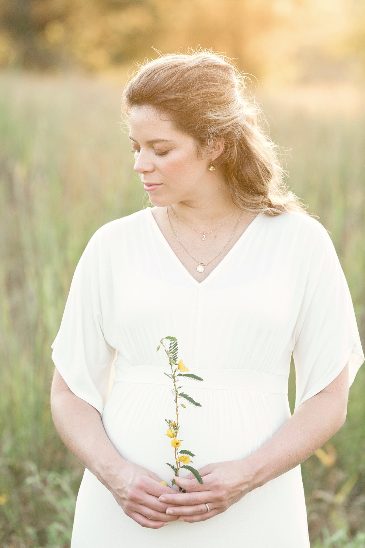 Expectant mother holds flowers during maternity photo shoot in Louisville KY