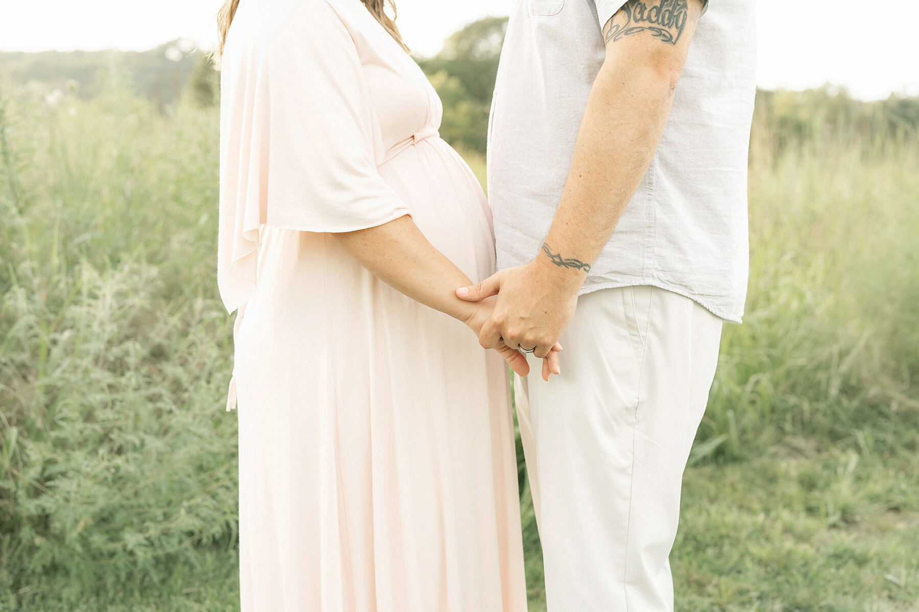 Expectant mom and dad hold hands during a sunset outdoor maternity photo session in Louisville KY.