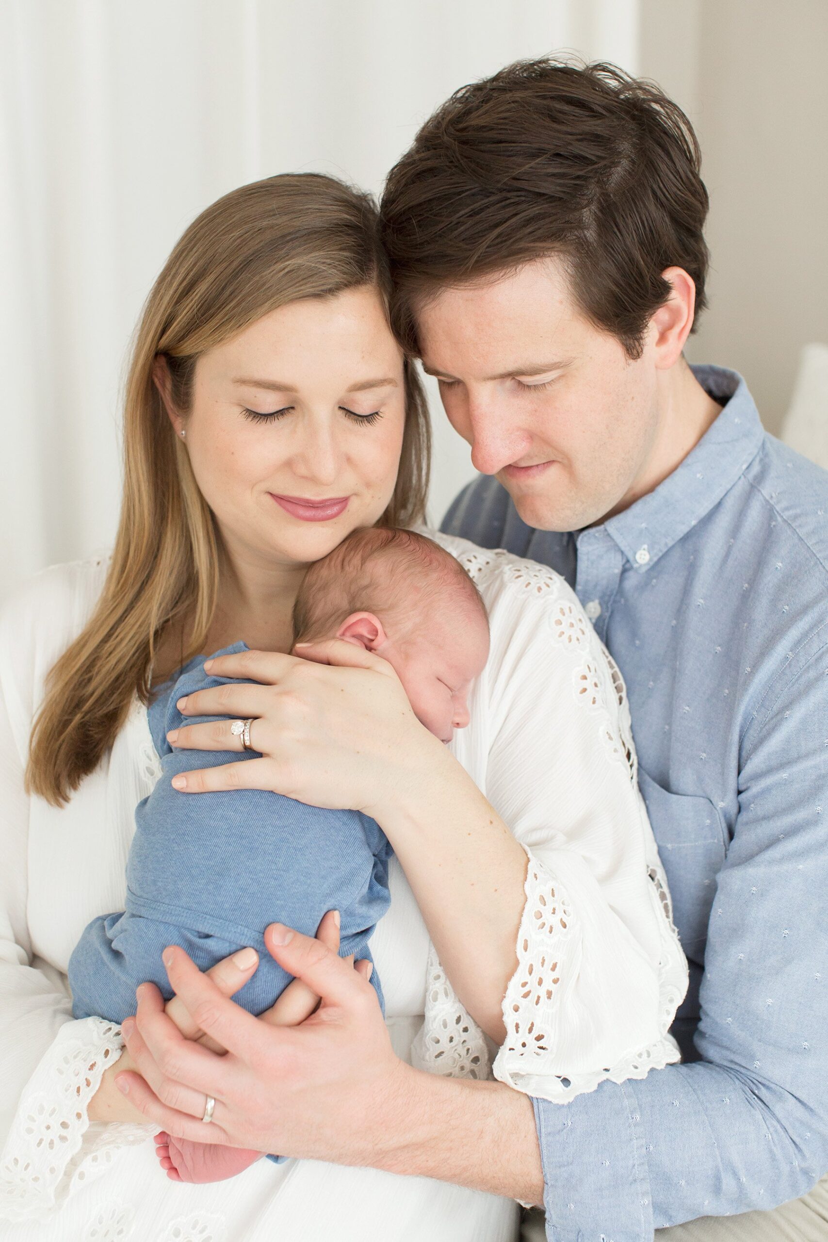 Mom and dad hold new baby boy during photo shoot at light and bright Louisville KY photography studio