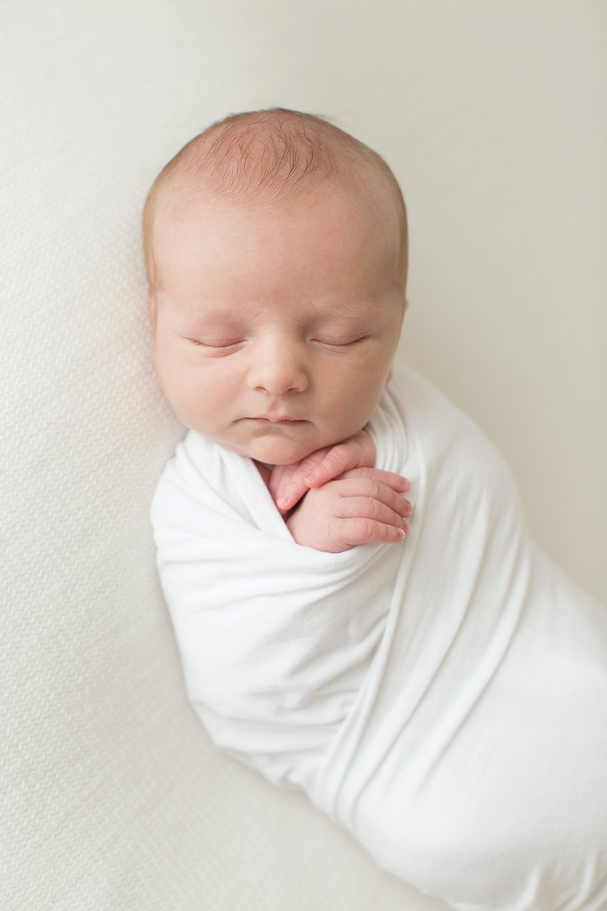 sleeping baby swaddled in white at Louisville KY photography studio with Julie Brock