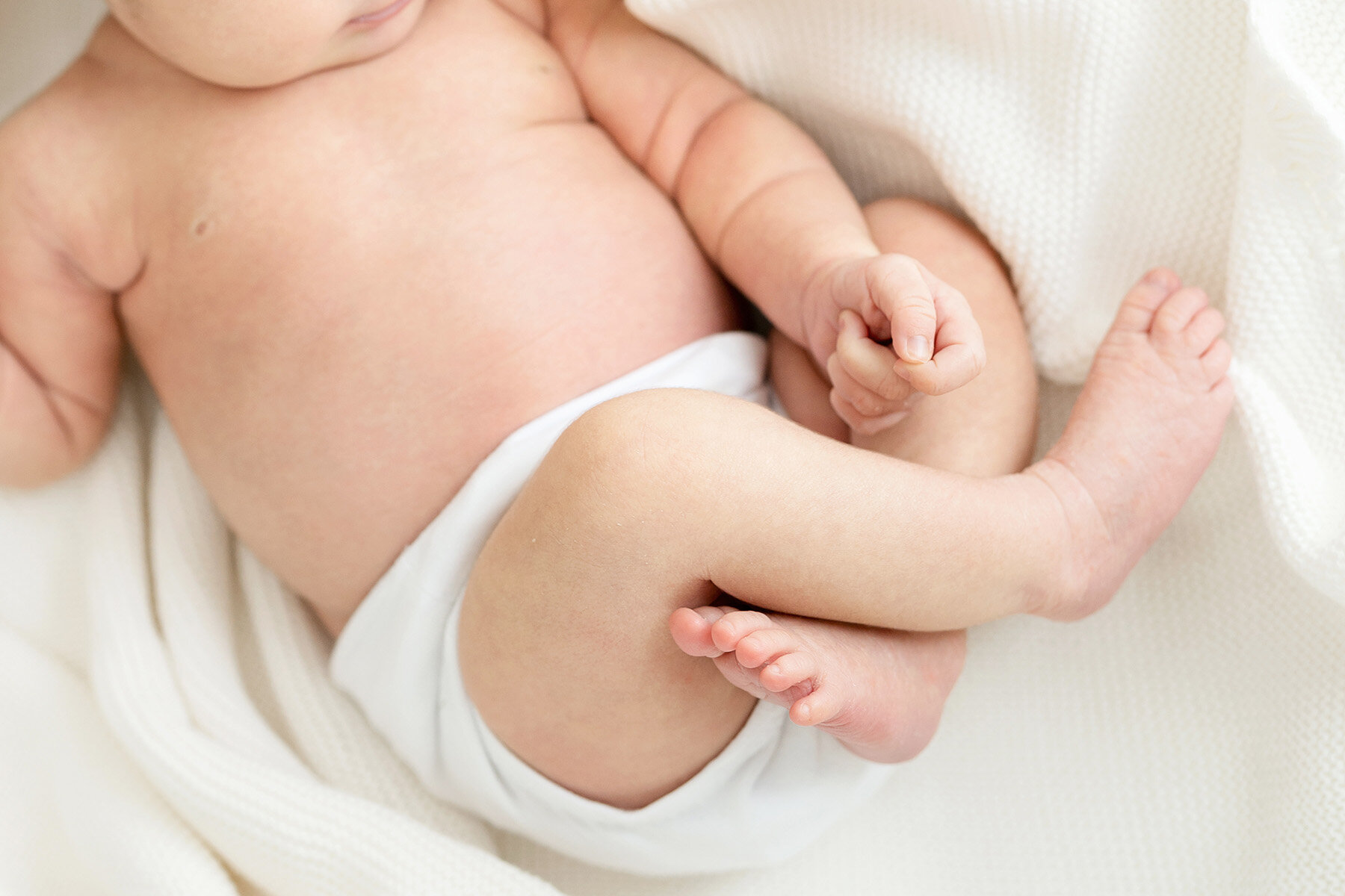 Detail photo of sleeping baby curled up to show hands and feet.