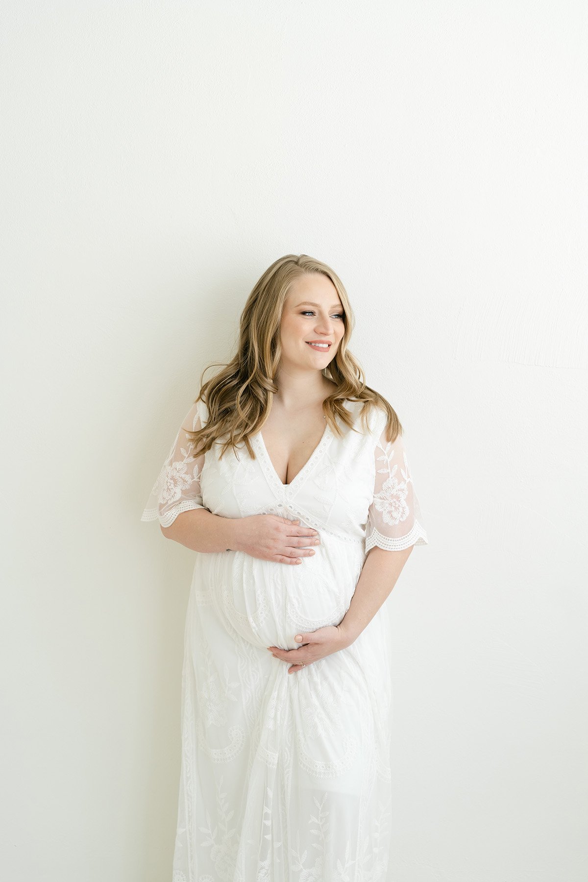 Smiling expectant mother wears perfect lace dress for maternity photo shoot in Louisville KY