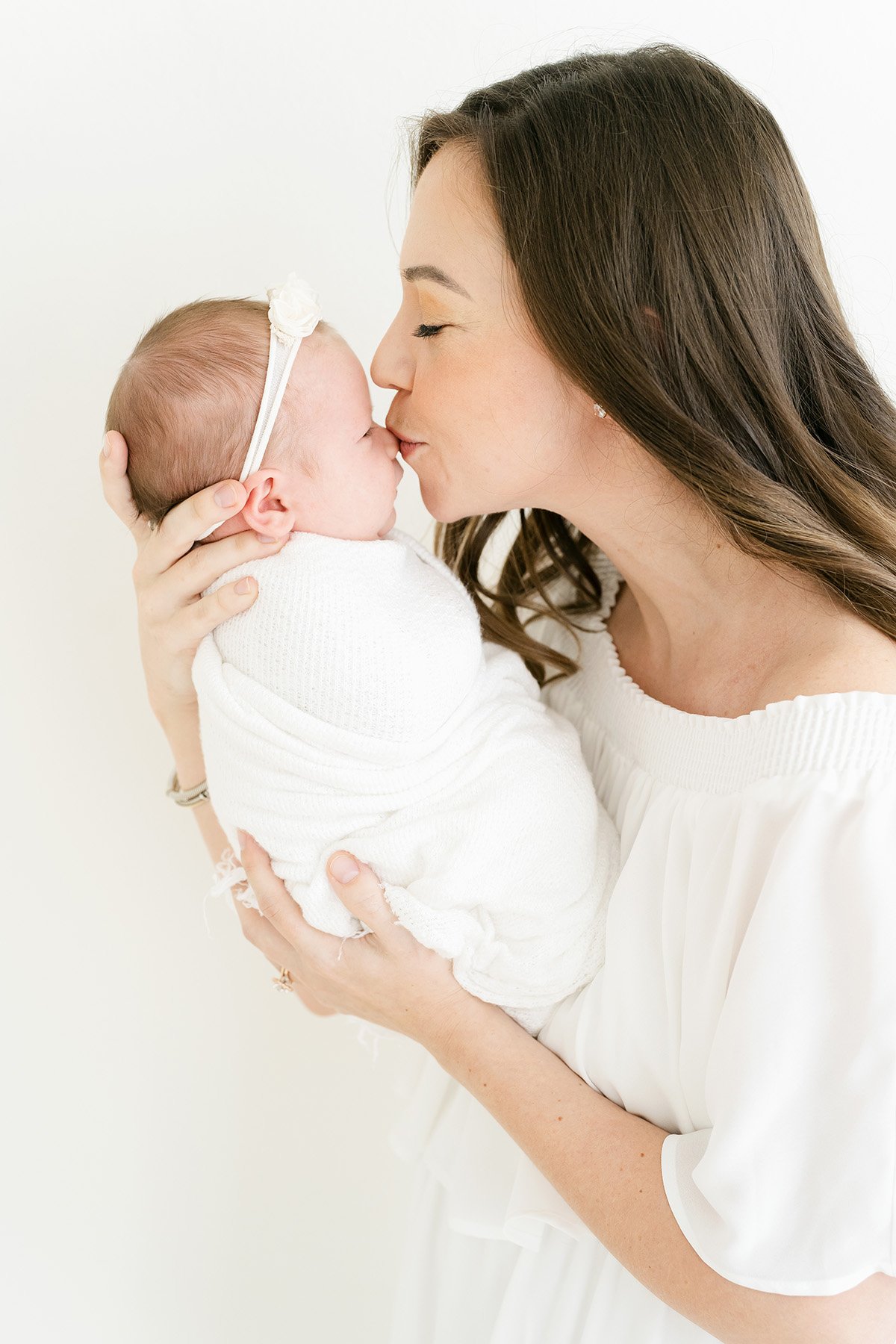 Mom kisses newborn baby girl during newborn photo shoot in Louisville Ky