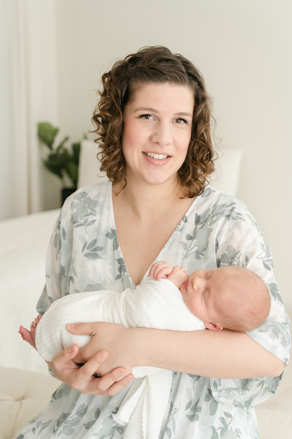 Mom smiles and holds newborn baby boy during photo shoot at Julie Brock Photography in St Matthews KY