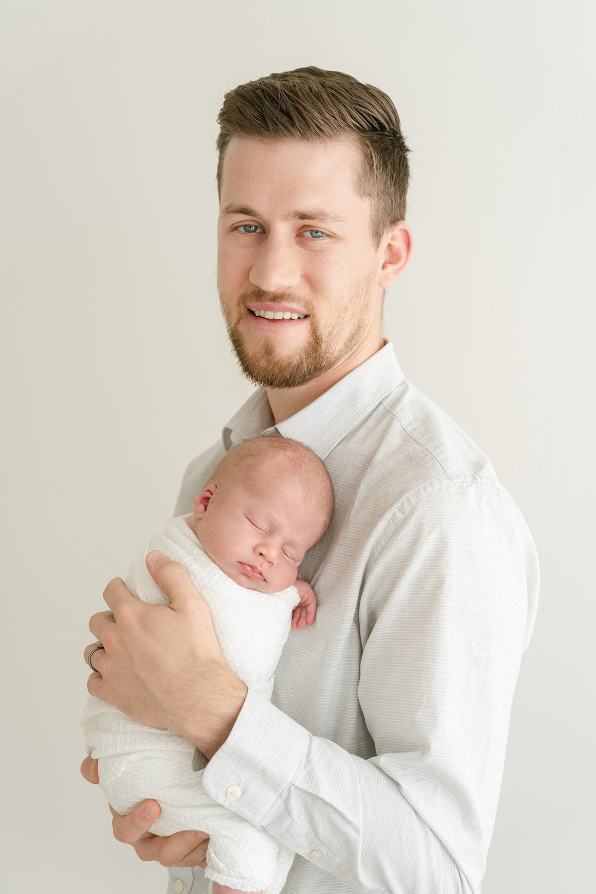 Dad smiles and holds newborn baby boy during photo shoot at Julie Brock Photography in Louisville KY