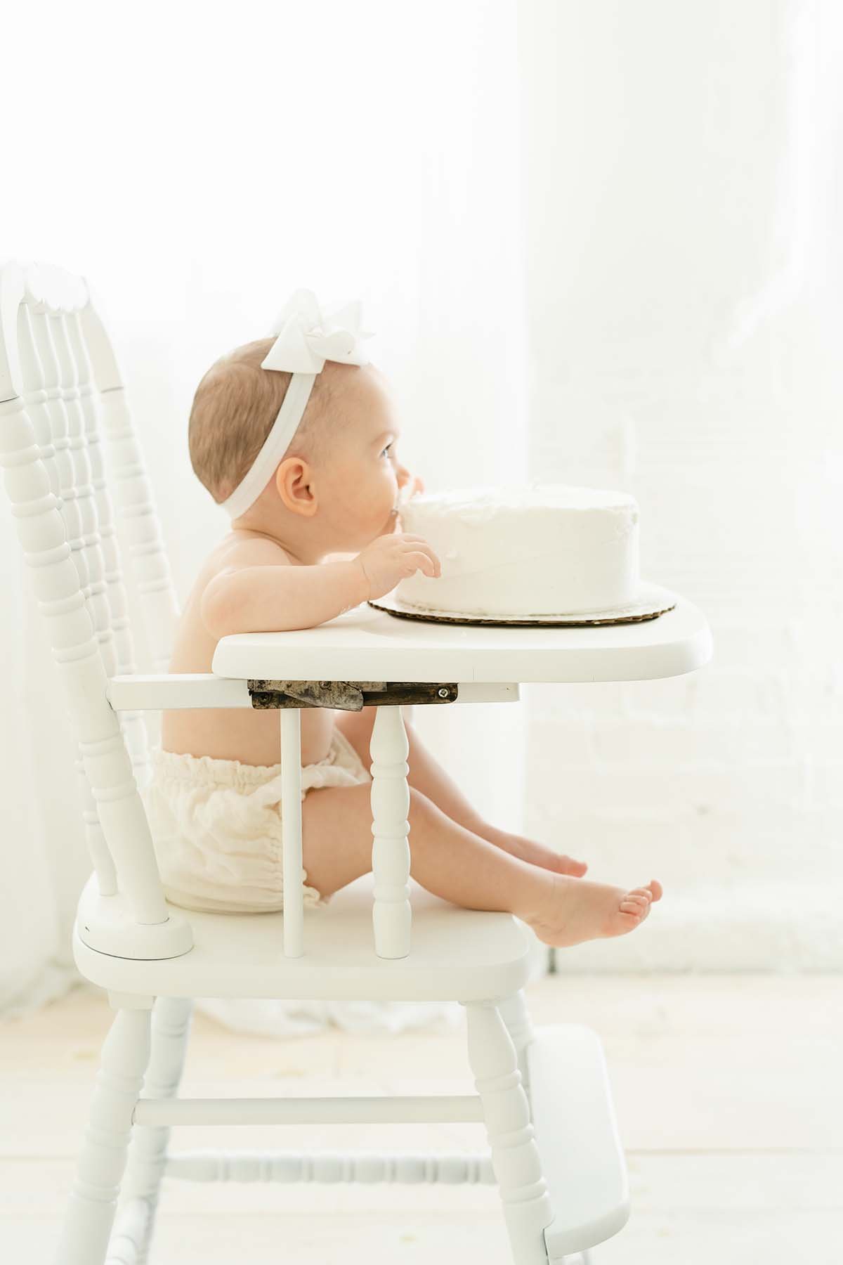 Baby girl plays with cake during first birthday photo shoot in Louisville KY with Julie Brock