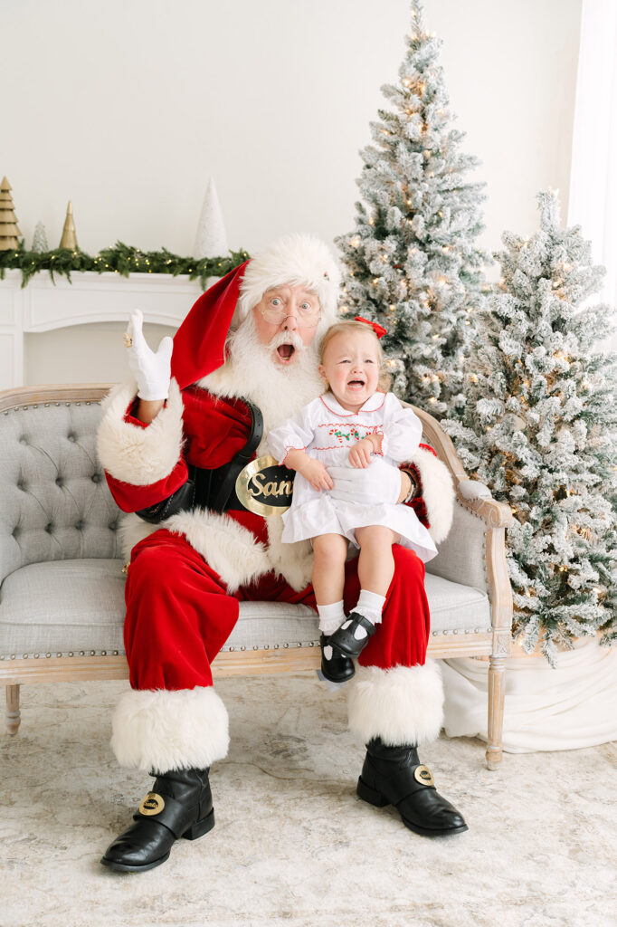 Funny, candid moment of little girl and Santa making funny faces