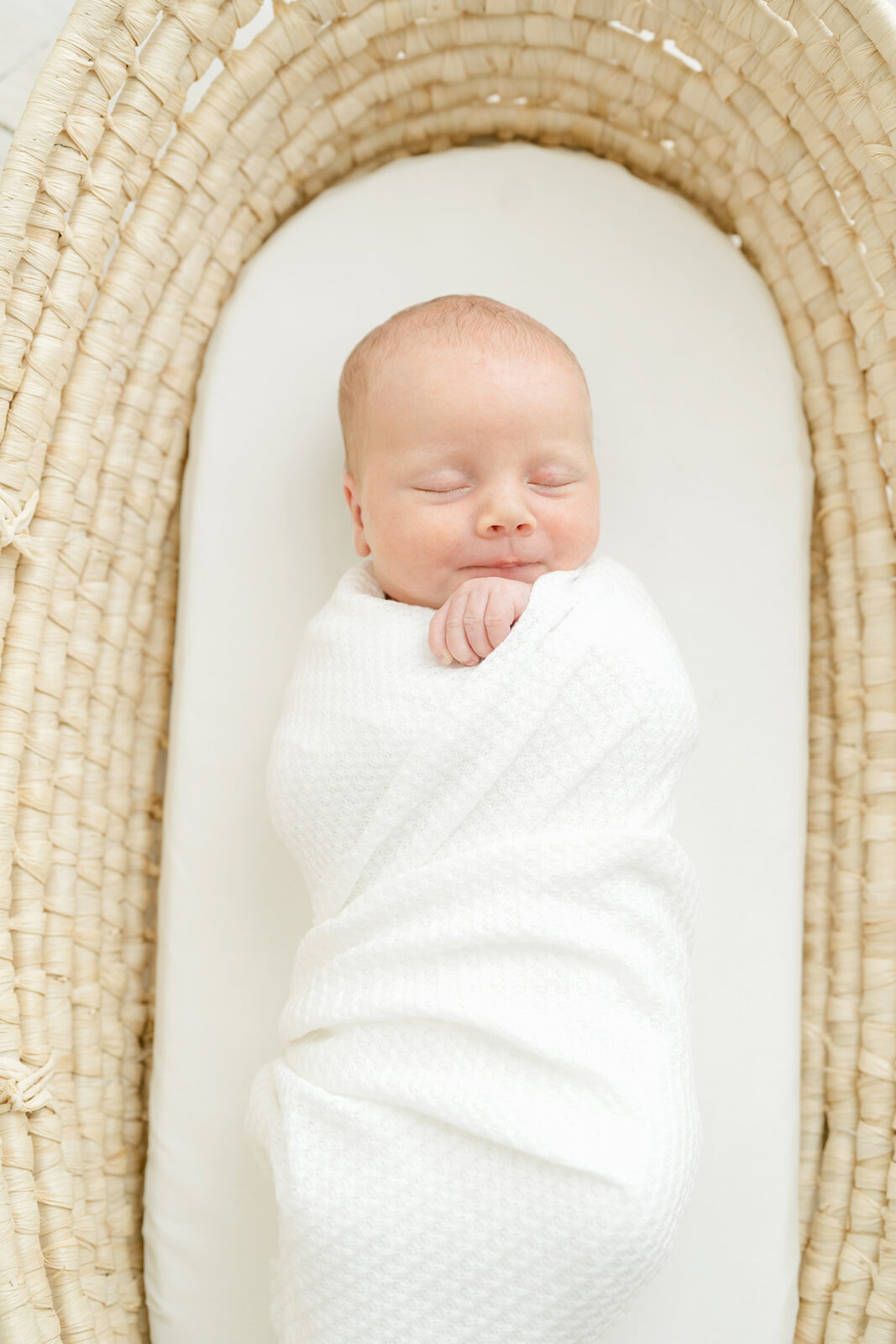 Baby smiles while sleeping in Moses basket at Julie Brock Photography Studio in Kentucky
