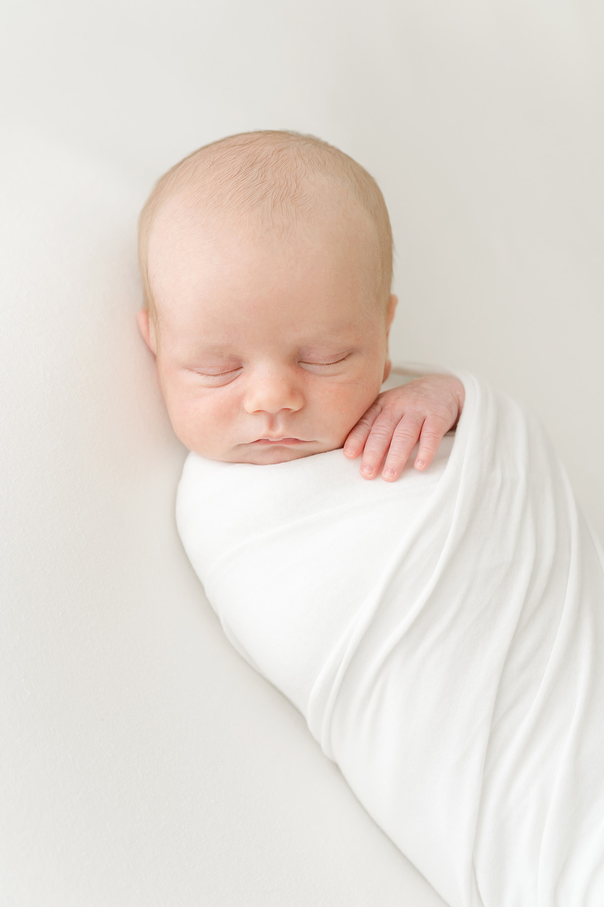 Louisville Ky newborn baby wrapped in a white swaddle sleeps during newborn photo session at Julie Brock Photography in Louisville KY