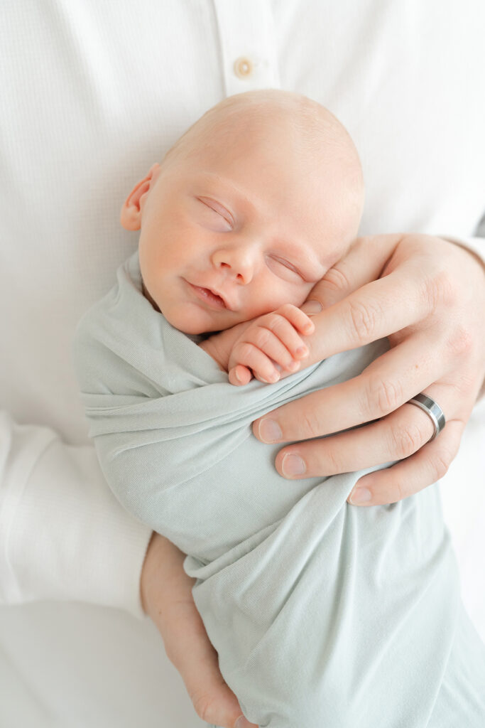 Newborn baby boy smiles while sleeping at Julie Brock Photography studio in Louisville KY