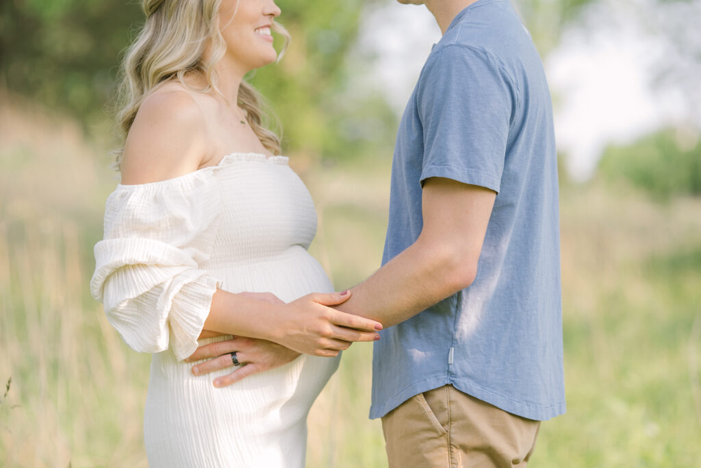 Happy couple holds their baby bump during a pregnancy photo shoot with Julie Brock Photography