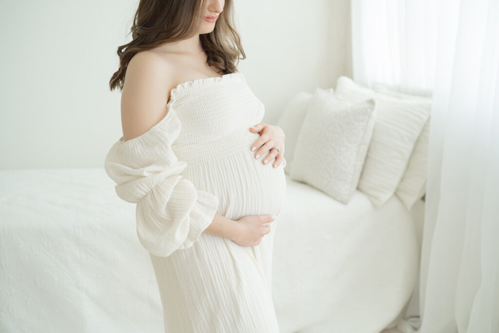 Louisville Ky mother wears romantic off shoulder, ivory dress during a maternity photo shoot at Julie Brock Photography.