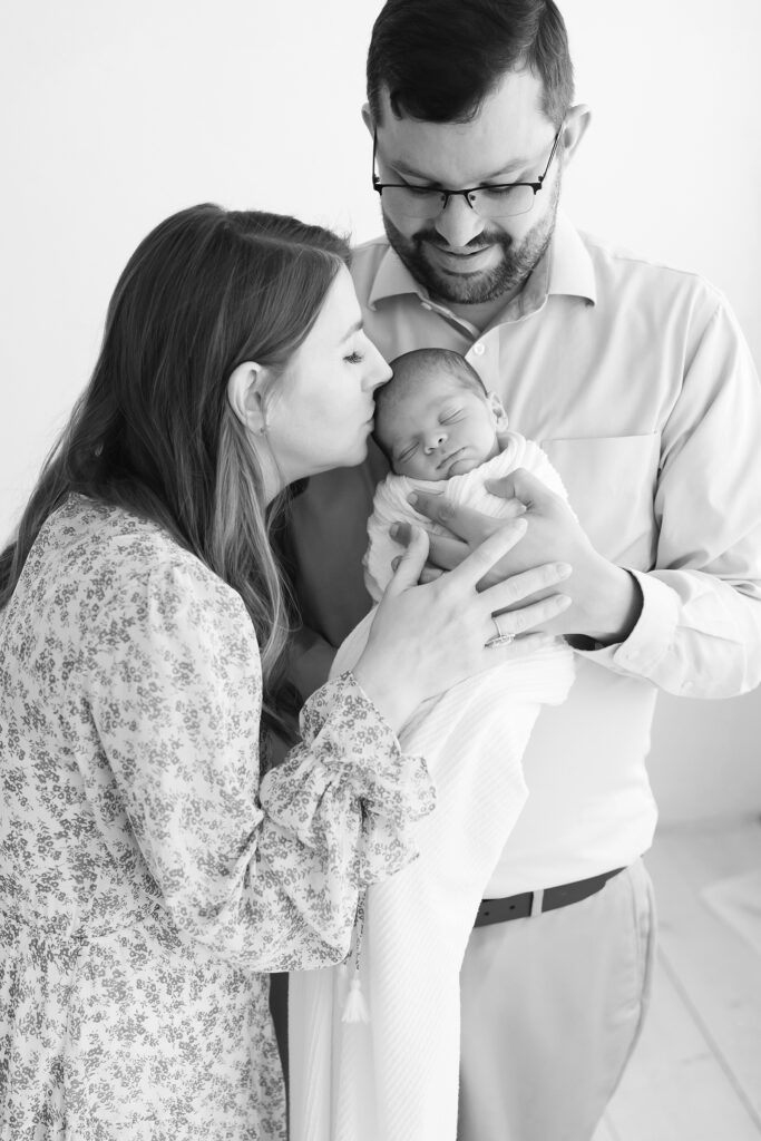 Louisville Ky parents kiss their newborn baby boy while Julie Brock takes their photograph