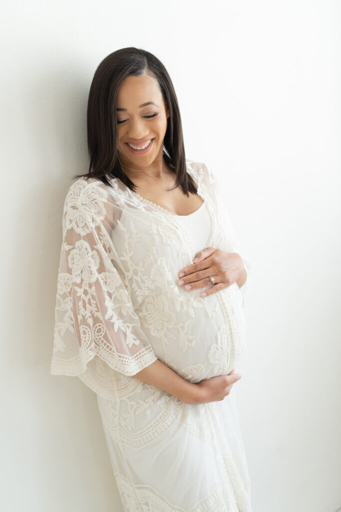 Pregnant mother laughs and smiles wearing a lace robe and fitted slip for her Maternity Session with Julie Brock Photography near Louisville KY