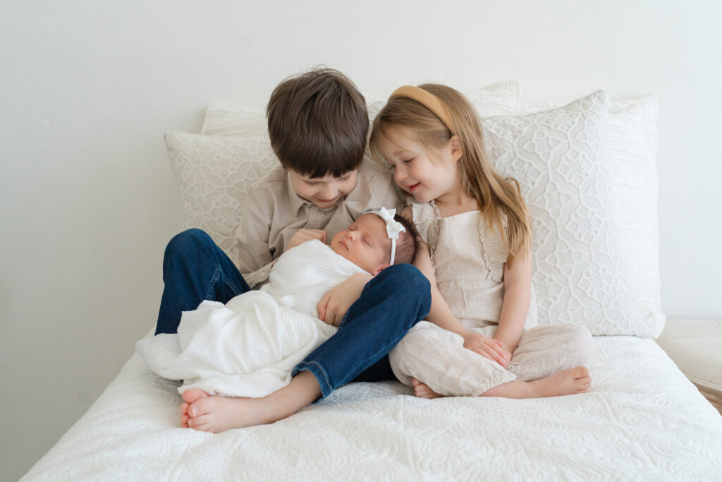Big brother and big sister proudly hold their newborn baby sister for a photo with Julie Brock Photography in Louisville KY