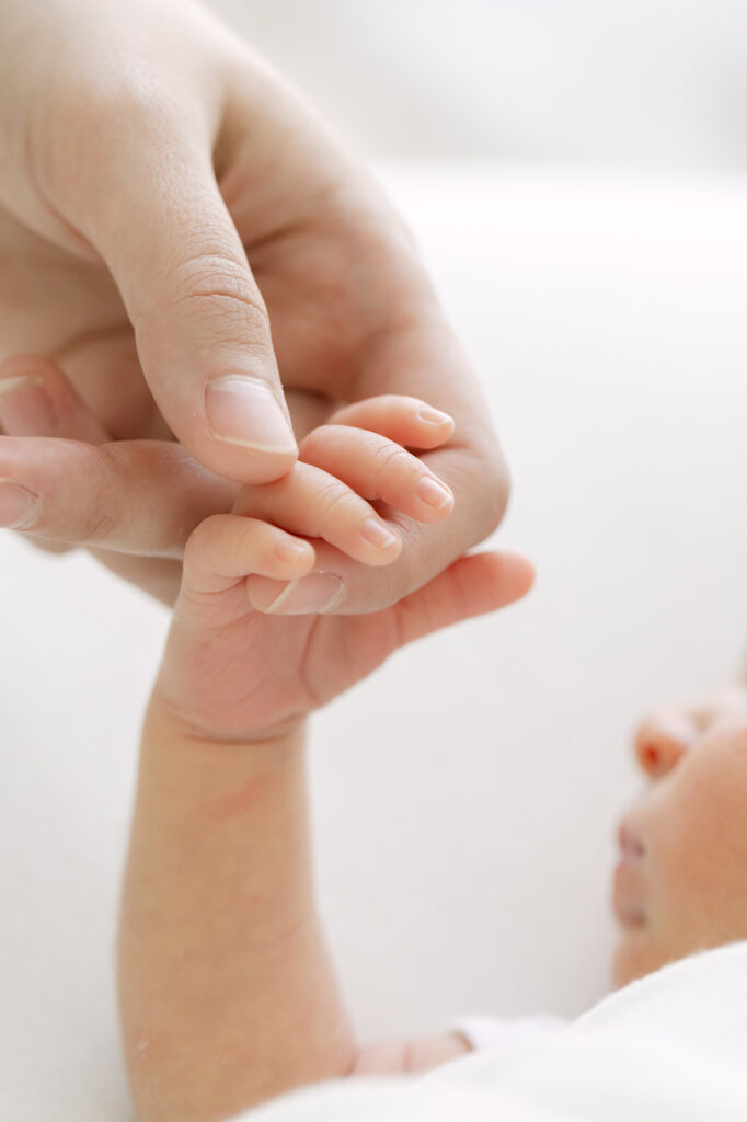 Louisville newborn photographer Julie Brock takes up-close detail image of dad holding his newborn baby's hand