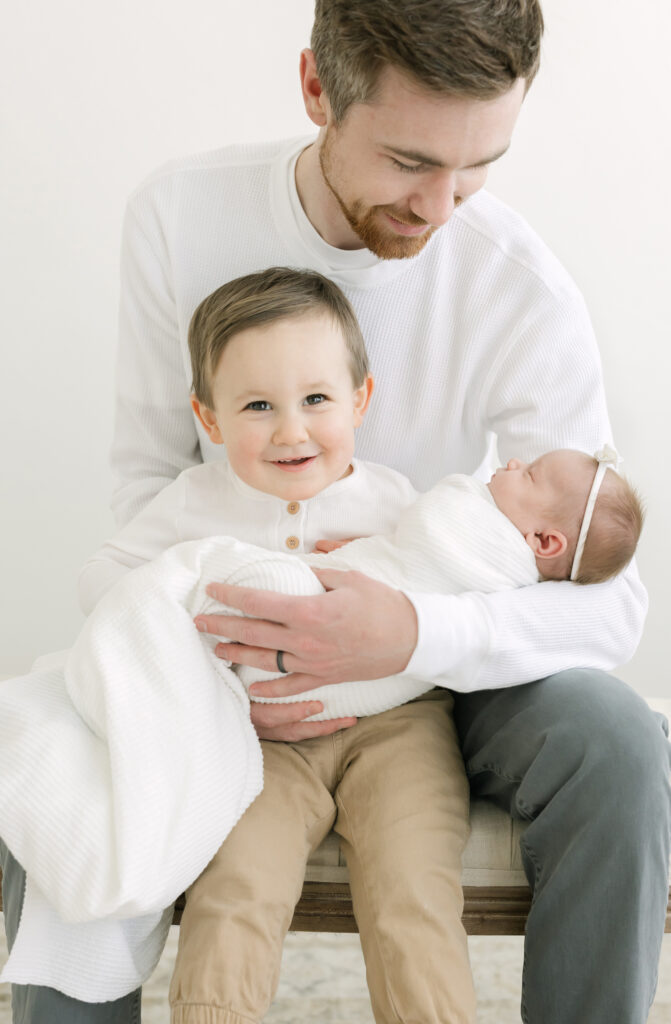 Louisville dad holds son and newborn baby girl for family photos at Julie Brock Photography studio