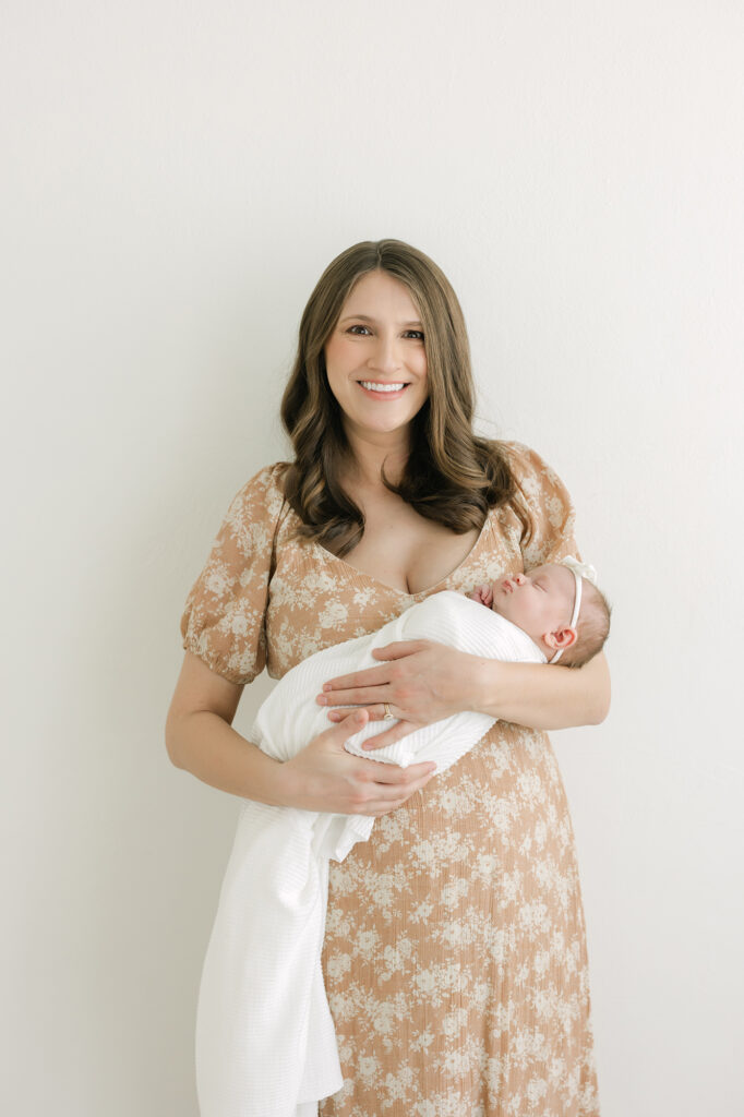 Mom wears peach dress from studio client closet and holds baby for louisville newborn photography with Julie Brock