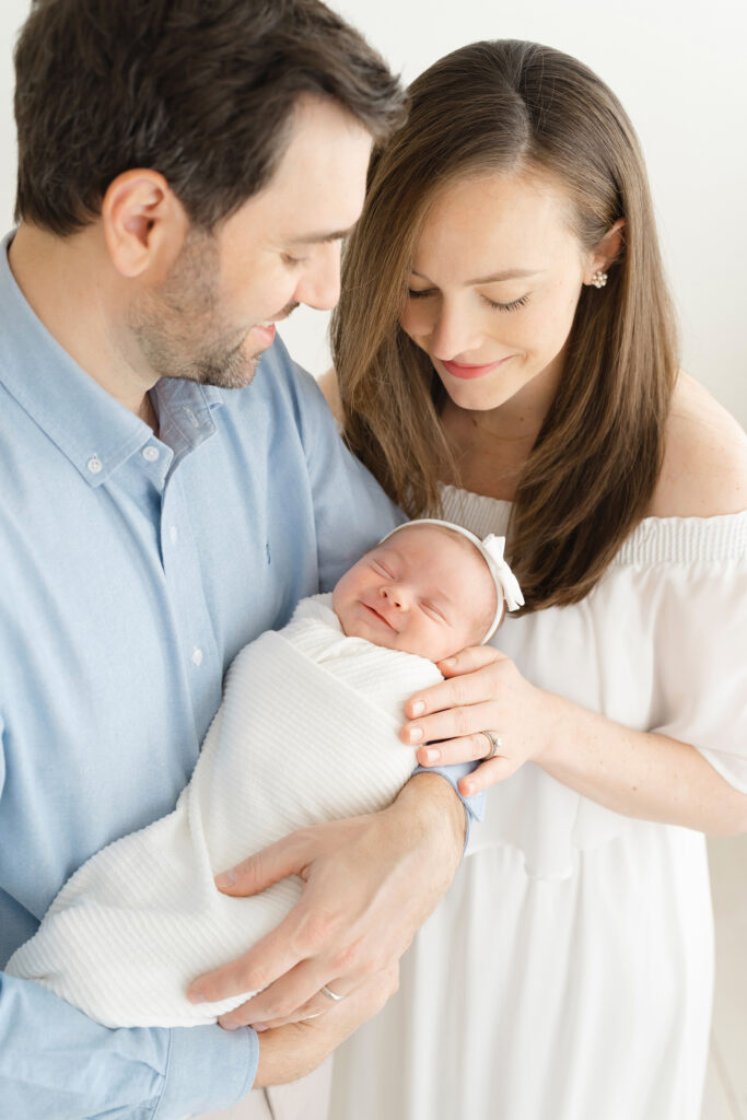 Voted best newborn photographer in Louisville KY, Julie Brock Takes photo of a sleeping baby who's smiling. Emphasizing tender family moments and soft, natural styling.