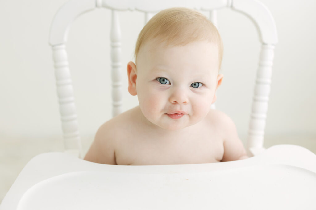 baby smiles at photographer during her cake smash first birthday photos in louisville ky