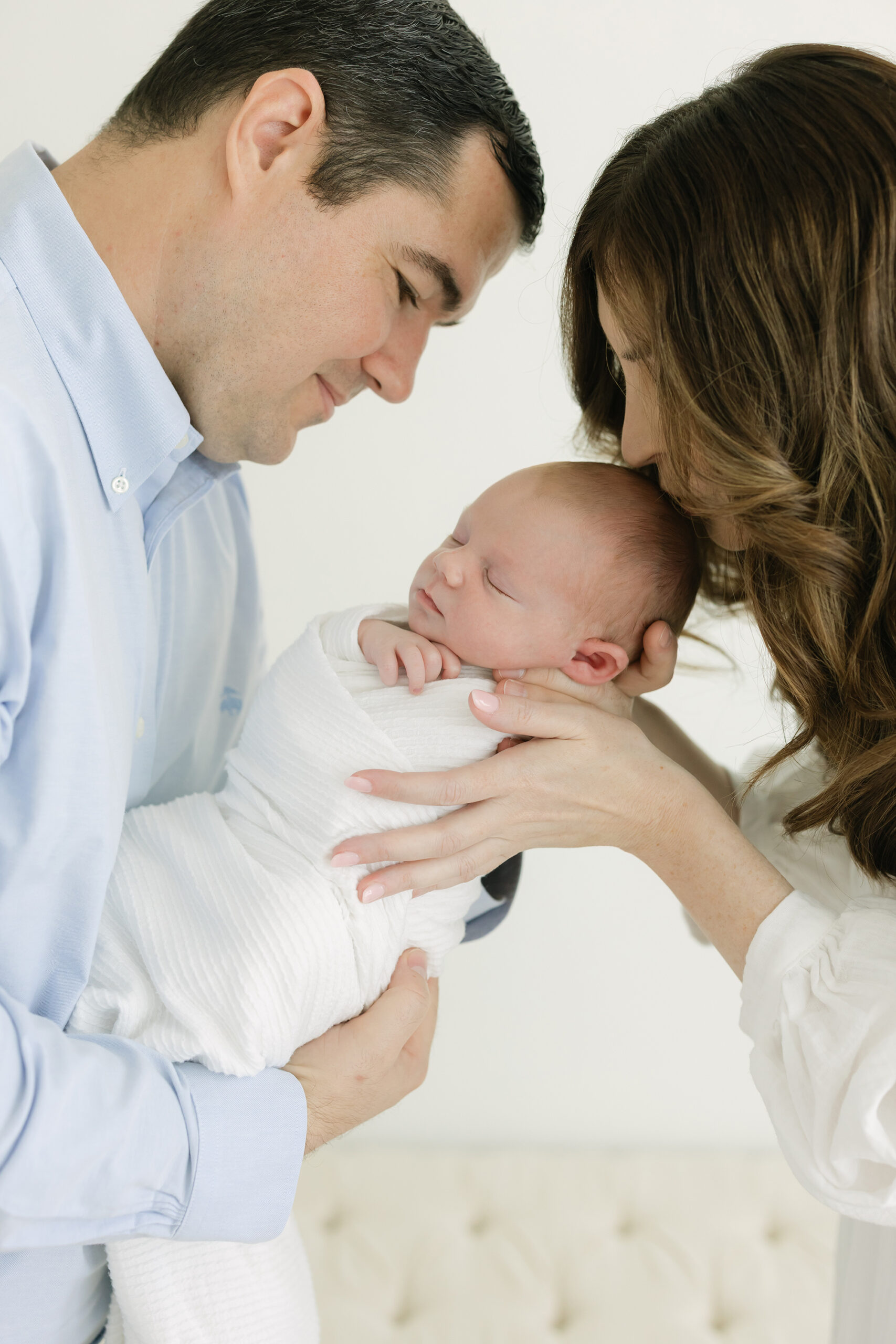 natural, bright newborn photo of Louisville Ky parents kissing their baby boy at Julie Brock Photography studio