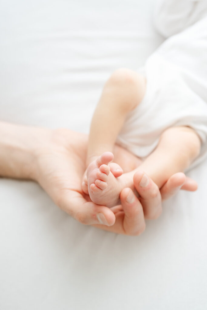 naturally posed newborn photography studio shows detail images of baby profile and dad holding baby's feet
