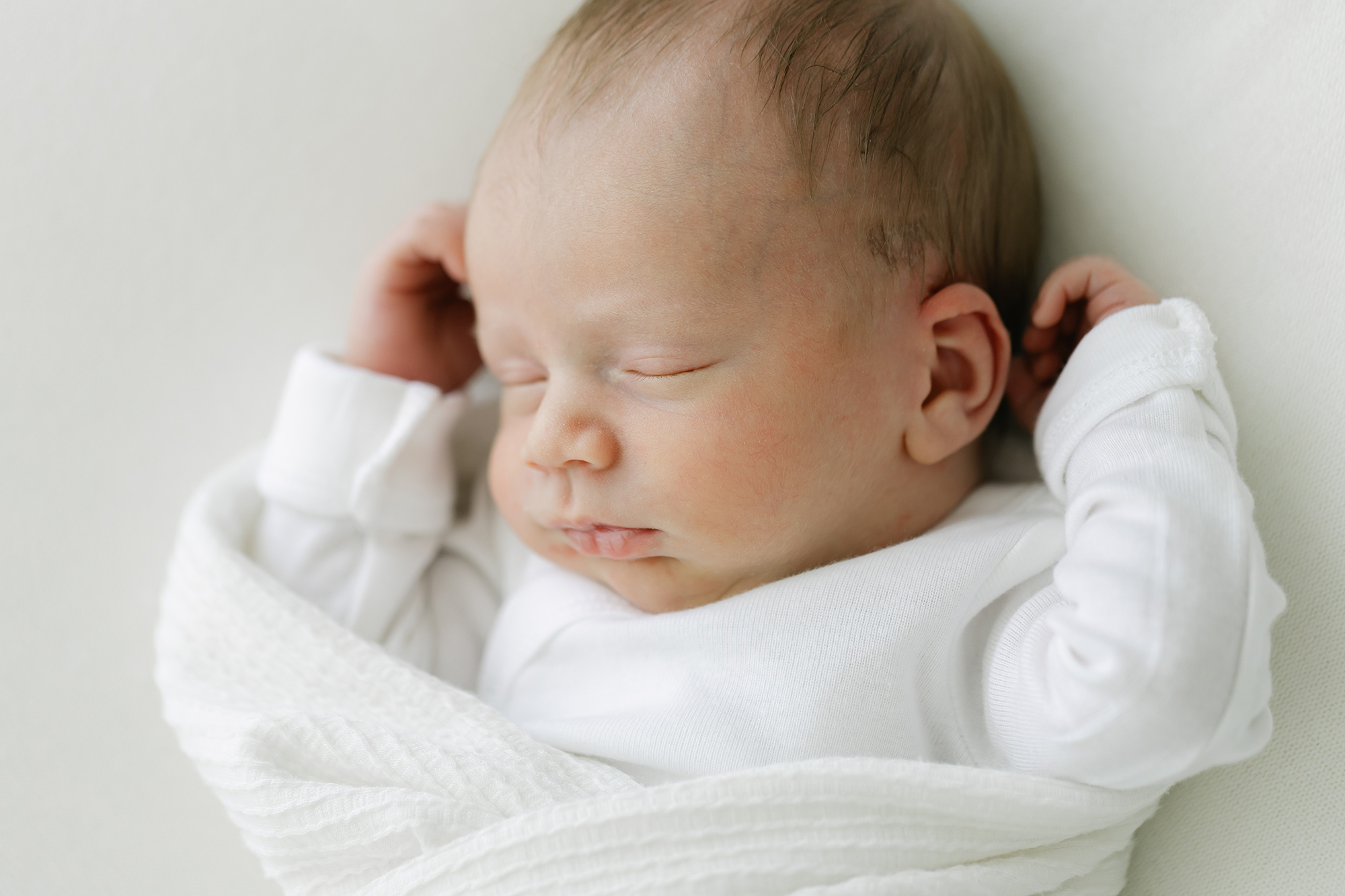 Newborn portrait of sleeping baby boy wrapped in white blanket at newborn bright and airy studio near St Matthews in Louisville KY at Julie Brock Photography Studio