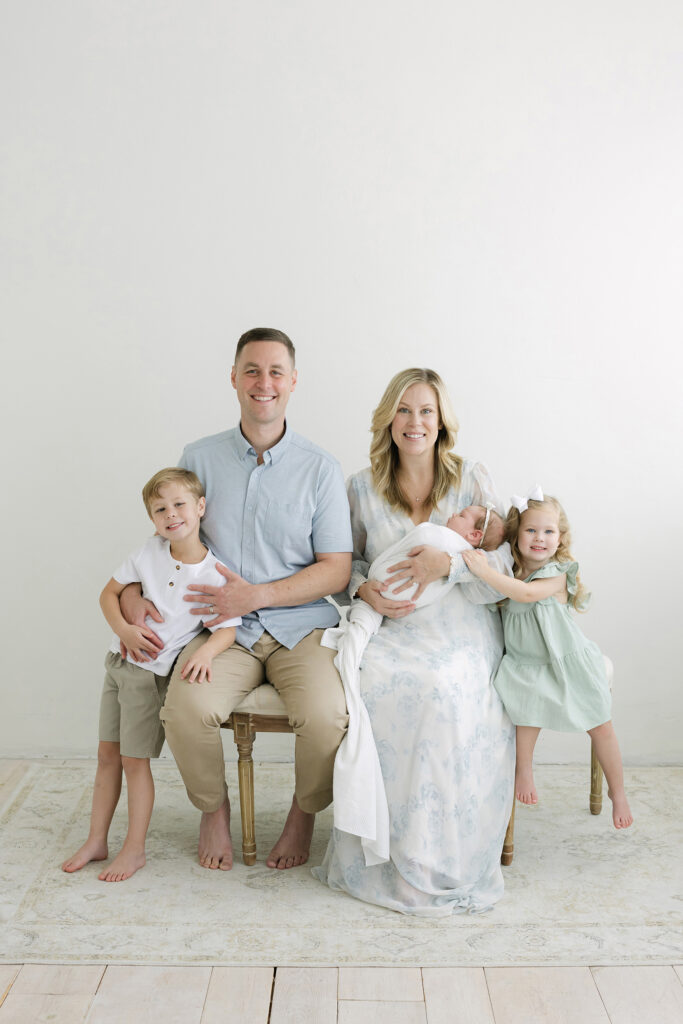 Siblings smile and laugh while Louisville newborn photographer Julie Brock takes photo of their baby sister. 