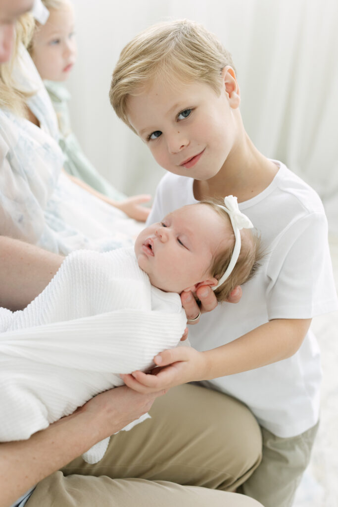 Proud big brother holds his newborn baby sister during newborn photo session at Julie Brock Photography Studio near Louisville kentucky
